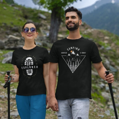 Two people wearing black t-shirts with mountain designs against a scenic background